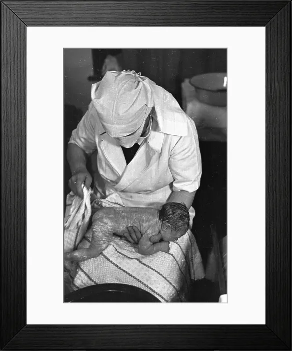 Framed Print : Wipe Down. 4th August 1946: A midwife wipes a new born baby with a sterilised Framed Print : Wipe Down. 4th August 1946: A midwife wipes a new born baby with a sterilised