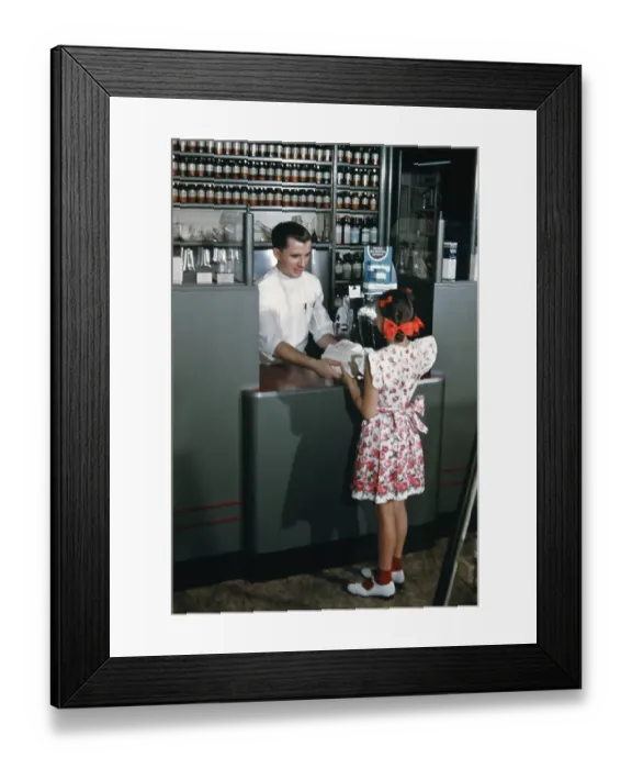 Framed Print : Pharmacy. NEW YORK - SEPTEMBER 1941: A Pharmacist serves a young girl in Framed Print : Pharmacy. NEW YORK - SEPTEMBER 1941: A Pharmacist serves a young girl in