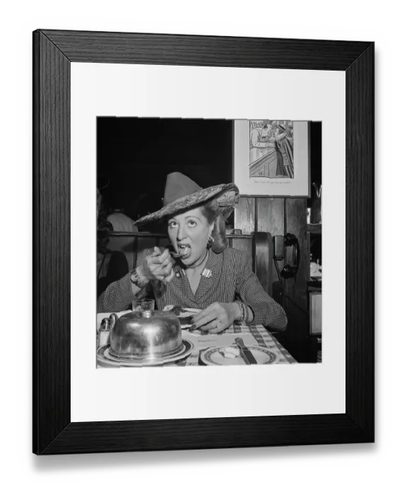 Framed Print : 21 Club. A woman, dressed in a suit and hat, takes a mouthful during at the 21 Club Framed Print : 21 Club. A woman, dressed in a suit and hat, takes a mouthful during at the 21 Club
