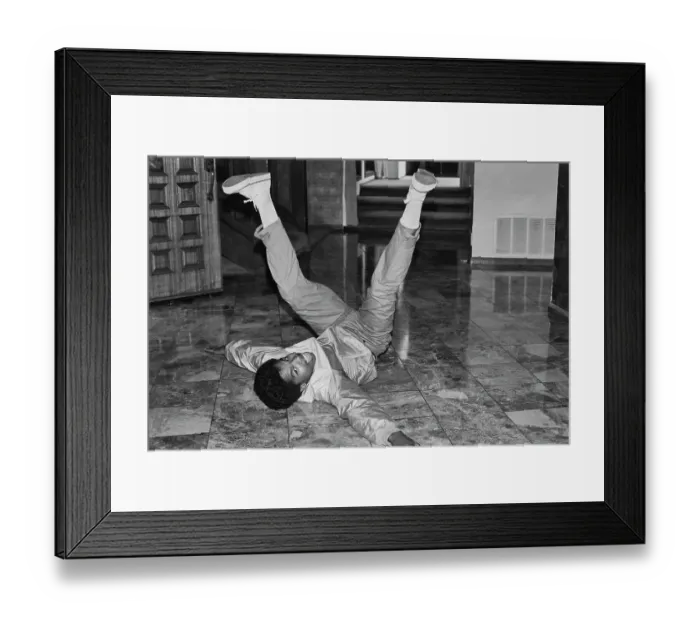 Framed Print : Breakin. A breakdancer with his legs in the air as he reclines on a marble-effect Framed Print : Breakin. A breakdancer with his legs in the air as he reclines on a marble-effect