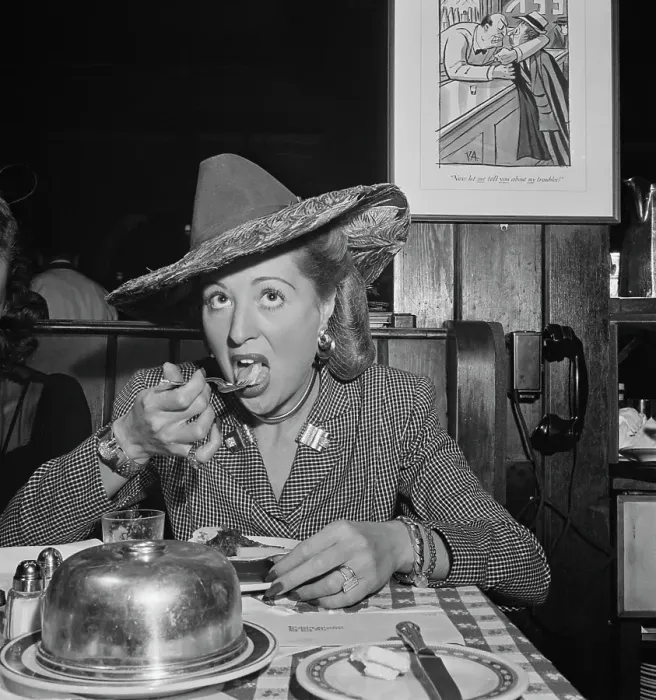 Framed Print : 21 Club. A woman, dressed in a suit and hat, takes a mouthful during at the 21 Club Framed Print : 21 Club. A woman, dressed in a suit and hat, takes a mouthful during at the 21 Club