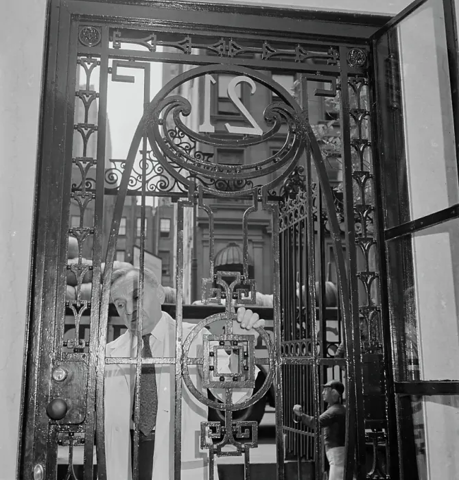 Framed Print : 21 Club. A caretaker closing the gate of the 21 Club, restaurant