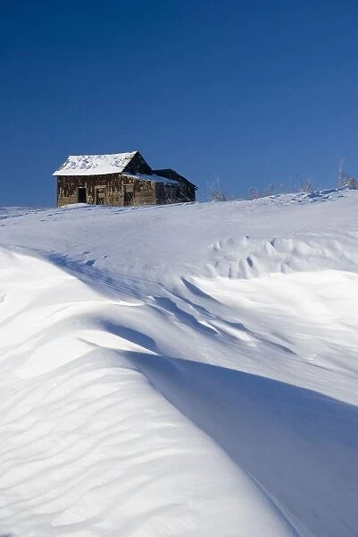 Abandoned farm building atop a snowy hill