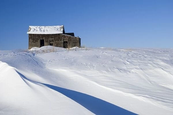 Abandoned farm building atop a snowy hill