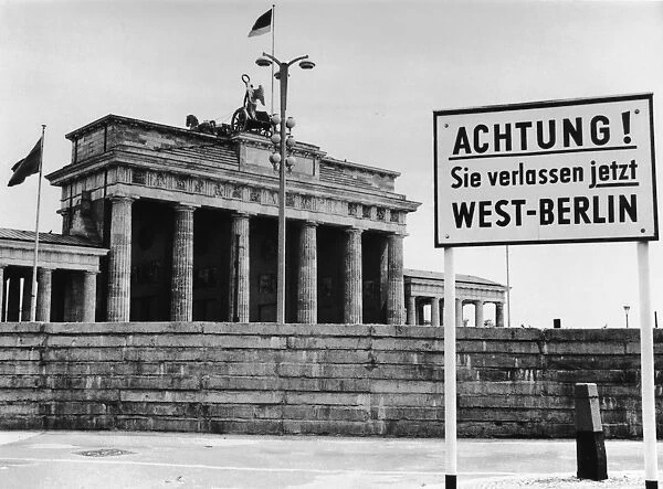 Achtung. A sign outside the Brandenburg Gate and the Berlin Wall reading Attention