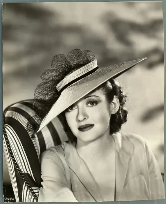 Framed Print : Actress Bette Davis Sitting in Chair and Wearing Hat Framed Print : Actress Bette Davis Sitting in Chair and Wearing Hat