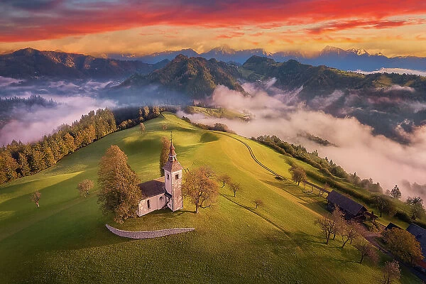 Aerial view of Saint Thomas church at sunrise in the fog, Skofja Loka, Upper Carniola, Slovenia