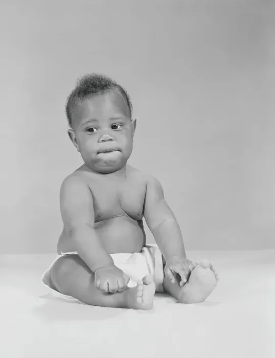 Framed Print : African-American baby sitting with hands on legs, biting lower lip, portrait Framed Print : African-American baby sitting with hands on legs, biting lower lip, portrait