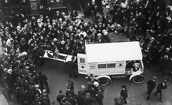 Ambulance. circa 1907: A motorised ambulance picking up an injured man