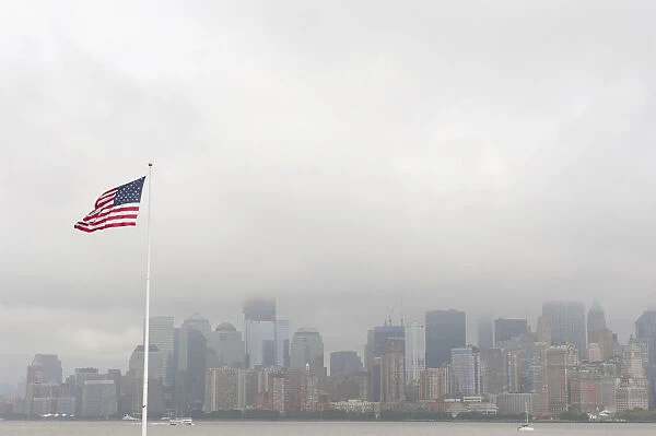 American national flag, view from Ellis Island towards the skyline of Manhattan in the fog, New York, USA, North America