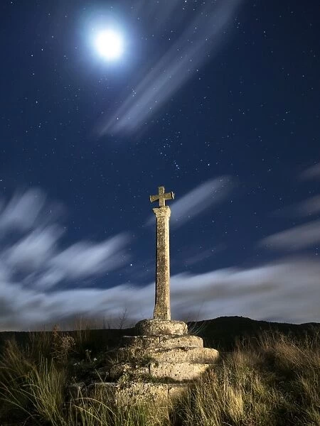 Ancient cross of stone to the dusk with full moon