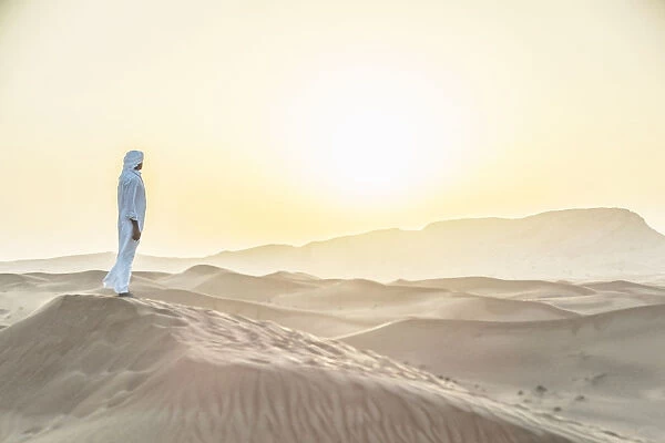 Arab man standing in sand dunes near Dubai