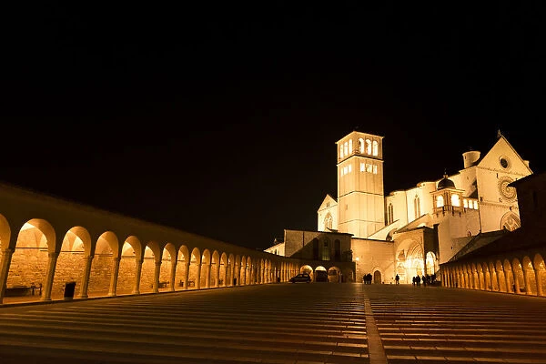 Arches along Piazza San Francesco at night with Basilica of San Francesco d Assisi in the background