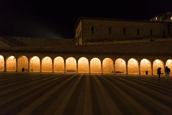 Arches along Piazza San Francesco at night leading to Basilica St. Francis of Assisi