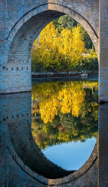 An archway of the Valentre Bridge in Cahors, France with the Lot River flowing underneath