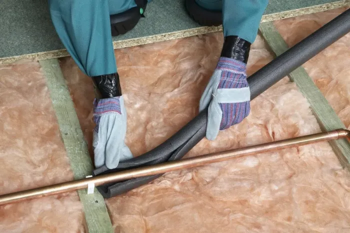 Framed Print : Attaching pipe insulation to a copper pipe above joists and insulation blanket Framed Print : Attaching pipe insulation to a copper pipe above joists and insulation blanket