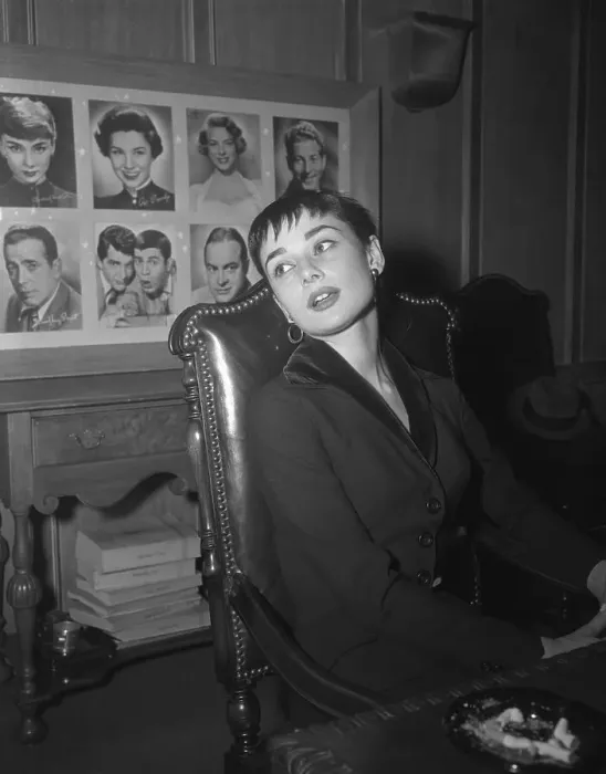 Framed Print : Audrey Hepburn Sitting with Wall of Portraits Behind Her Framed Print : Audrey Hepburn Sitting with Wall of Portraits Behind Her