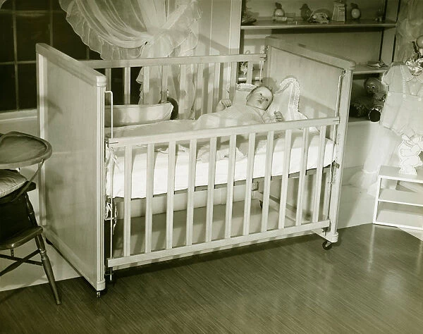 Baby (3-6 months) lying in crib, (B&W)
