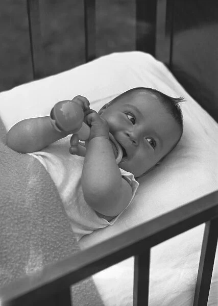 Baby (3-6 months) lying in crib, (B&W), elevated view