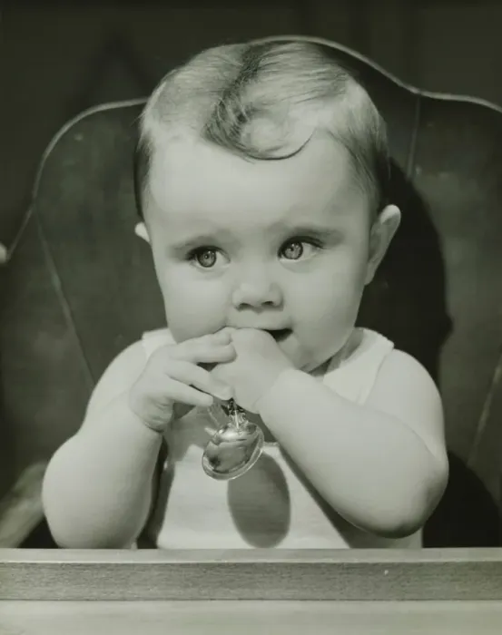 Framed Print : Baby (6-9 months) sitting in high chair, holding spoon, (B&W), portrait Framed Print : Baby (6-9 months) sitting in high chair, holding spoon, (B&W), portrait