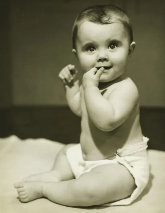 Framed Print : Baby boy (12-18 months) sitting on bedspread, sucking finger, (B&W), close-up