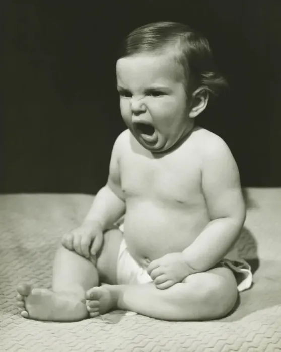 Framed Print : Baby boy (12-18 months) sitting on bedspread, yawning, (B&W) Framed Print : Baby boy (12-18 months) sitting on bedspread, yawning, (B&W)