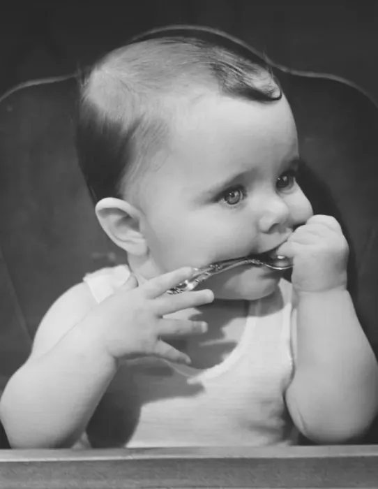 Framed Print : Baby boy (6-9 months) sitting in highchair, biting spoon (B&W) Framed Print : Baby boy (6-9 months) sitting in highchair, biting spoon (B&W)