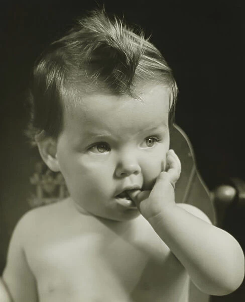Baby boy (6-9 months) with thumb on mouth, (B&W), portrait