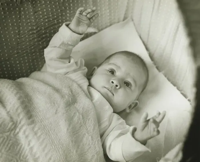 Framed Print : Baby girl (6-12 months) lying in bed with arms raised, (B&W) Framed Print : Baby girl (6-12 months) lying in bed with arms raised, (B&W)