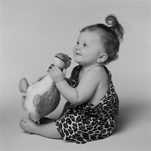 Baby girl playing with toy dinosaur, smiling