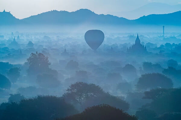 A balloon flying down near the old Bagan pagoda with morning fog