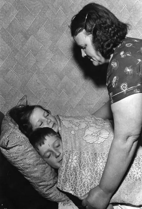 Framed Print : Bedtime. 30th November 1940: A woman putting her children to bed in cramped slum housing Framed Print : Bedtime. 30th November 1940: A woman putting her children to bed in cramped slum housing