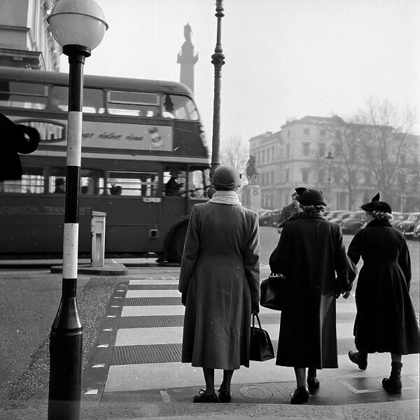 Belisha Beacon; Three ladies waiting to cross the road at a zebra crossing in London