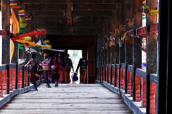 Bhutan, Paro, Paro Dzong, people crossing covered bridge, rear view