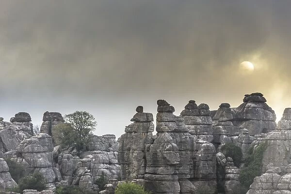 Bizarre limestone rock formations with the sun and fog, El Torcal Nature Reserve, Antequera, Andalusia, Spain