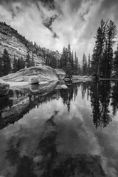 Black and white image of granite outcropping with boulders by lake, Yosemite National Park, California, USA