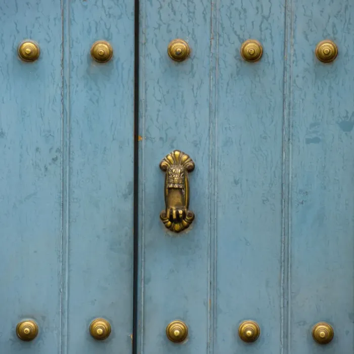 Framed Print : A Blue Door With Brass Decorative Knobs
