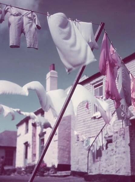 Blustery. circa 1957: Washing lines strung across a village street