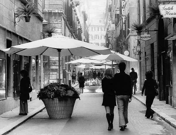 Via Borgognona. Tubs of flowers surmounted by beach umbrellas form a pedestrian