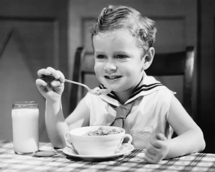 Framed Print : Boy (4-5) wearing sailor suit, eating at table, (B&W), portrait