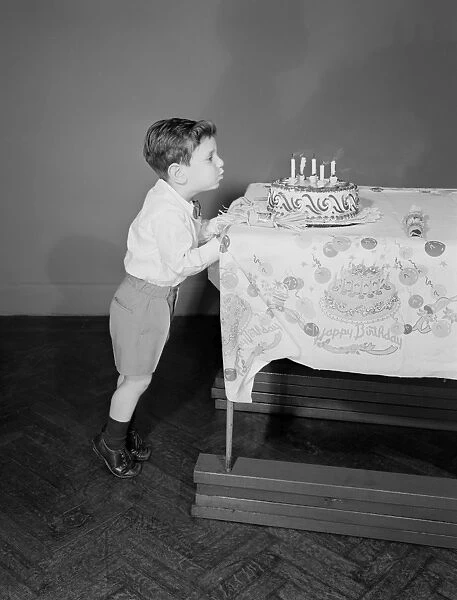 Boy (6-7) blowing candles on birthday cake