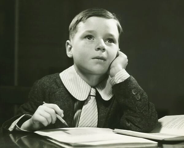 Boy (6-7) doing homework, (B&W), portrait