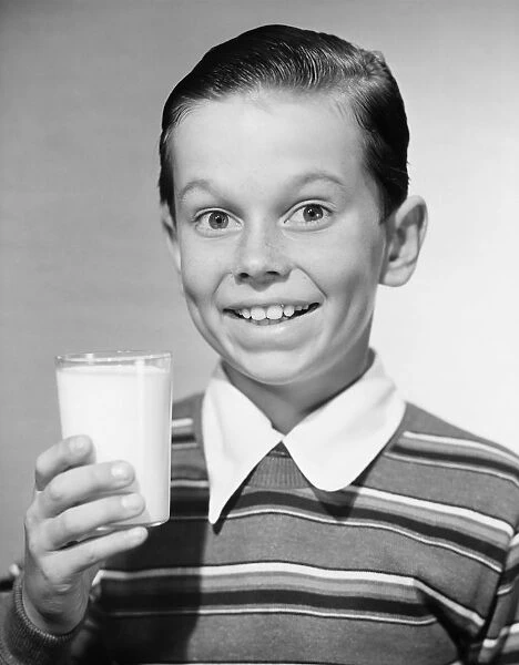 Boy (6-7) holding glass of milk, (B&W), portrait