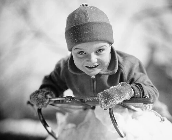 Boy (6-7) lying on sled in snow, (B&W), portrait