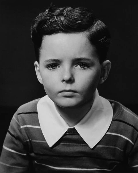 Boy (6-7) posing in studio, (B&W), portrait