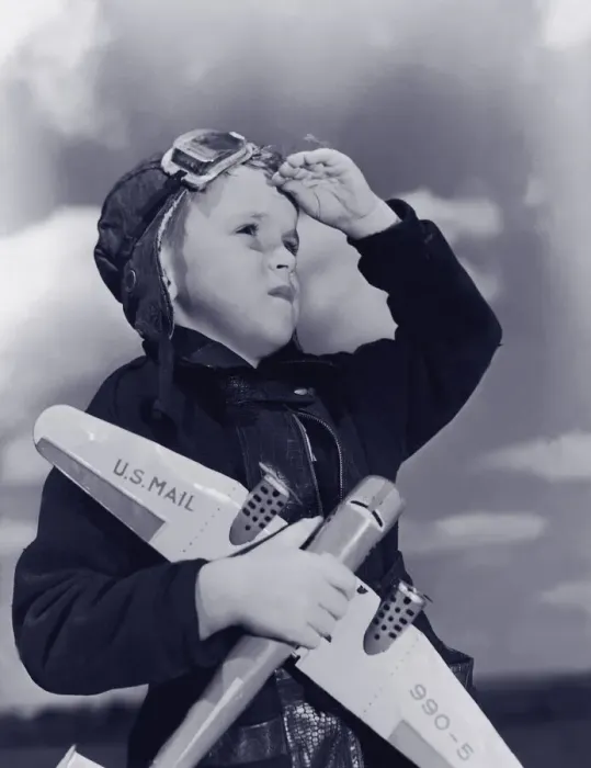 Framed Print : Boy (8-10) wearing flying cap and goggles holding toy plane (B&W)
