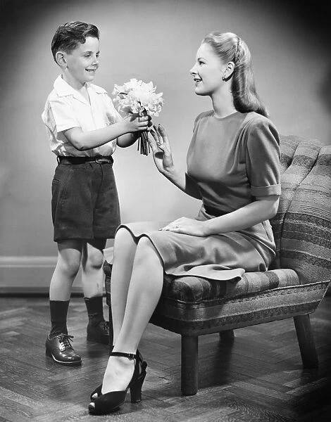 Boy (8-9) giving bunch of flowers to mother (B&W)