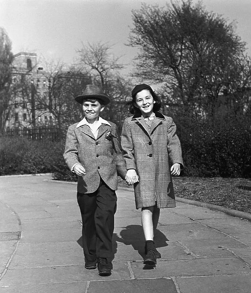 Boy and girl (12-13) holding hands outdoors, (B&W)