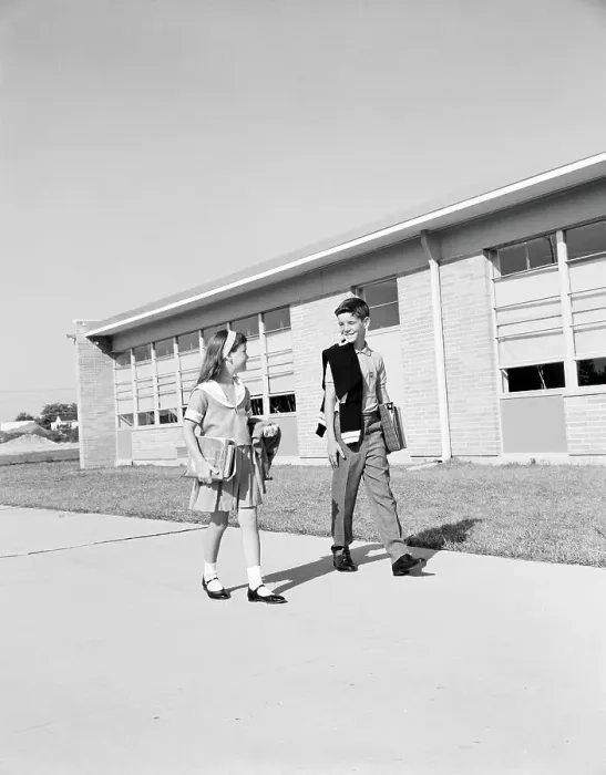 Framed Print : Boy and girl walking past school, carrying books and sweaters Framed Print : Boy and girl walking past school, carrying books and sweaters