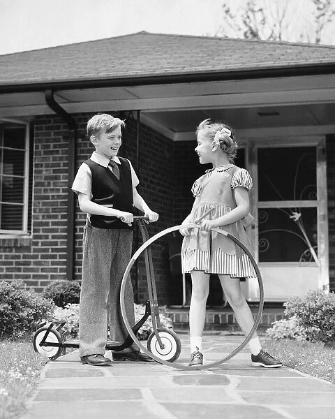 Boy on scooter, girl holding stick and hoop, outdoors